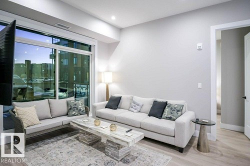 Living room featuring light wood-style flooring and baseboards - 101 7471 May Common, Edmonton, AB - Indoor Photo Showing Living Room