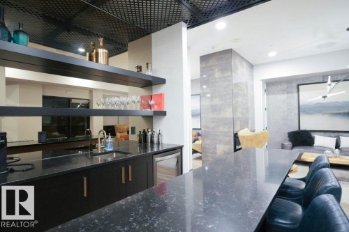 Kitchen with dark stone counters, a breakfast bar, open shelves, dark cabinets, and open floor plan - 101 7471 May Common, Edmonton, AB - Indoor