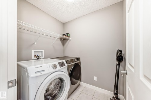 Laundry area with a textured ceiling, washer and dryer, and light tile patterned floors - 3520 49 Avenue, Beaumont, AB - Indoor Photo Showing Laundry Room