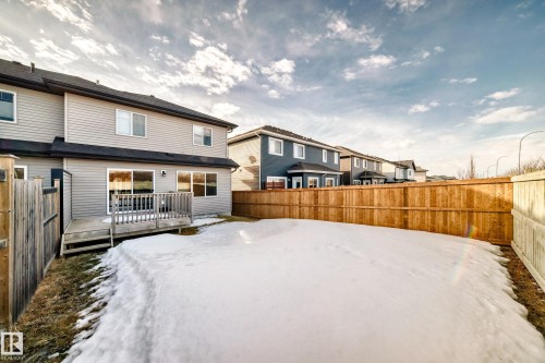 Snow covered rear of property with a fenced backyard, a deck, and a residential view - 3520 49 Avenue, Beaumont, AB - Outdoor With Deck Patio Veranda