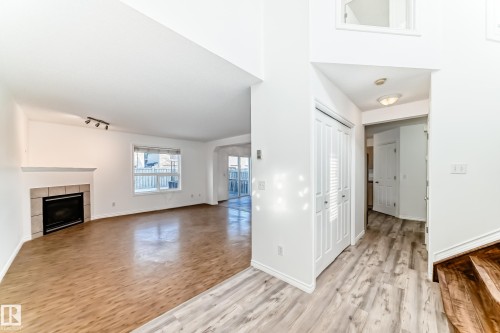 Unfurnished living room with light wood-type flooring, a tiled fireplace, and a high ceiling - 4604 202 Street, Edmonton, AB - Indoor With Fireplace