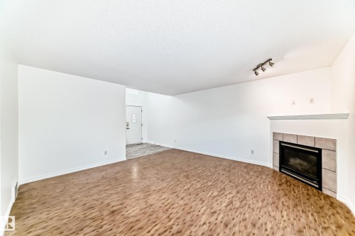 Unfurnished living room with a fireplace, wood finished floors, and a textured ceiling - 4604 202 Street, Edmonton, AB - Indoor With Fireplace