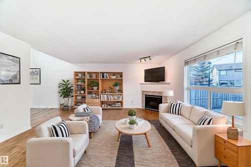 Living room featuring wood finished floors, a tiled fireplace, and rail lighting - 4604 202 Street, Edmonton, AB - Indoor Photo Showing Living Room With Fireplace