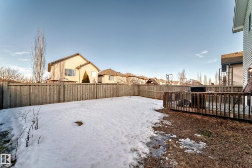 Yard layered in snow with a deck, a fenced backyard, and a residential view - 4604 202 Street, Edmonton, AB - Outdoor