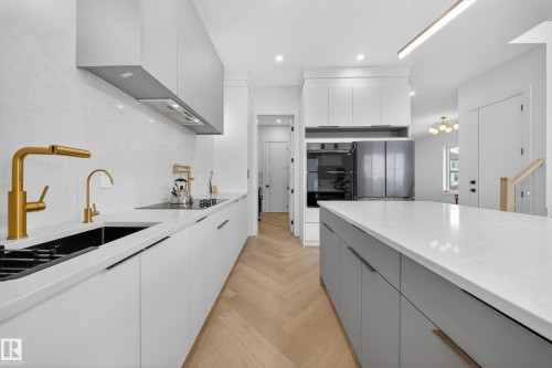 Kitchen featuring gray cabinets, modern cabinets, parquet flooring, light stone countertops, and freestanding refrigerator - 132 29 Street, Edmonton, AB - Indoor Photo Showing Kitchen With Upgraded Kitchen