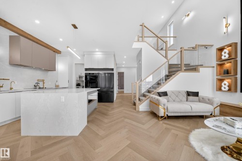 Kitchen featuring modern cabinets, a kitchen island, black refrigerator, parquet floors, and a towering ceiling - 132 29 Street, Edmonton, AB - Indoor