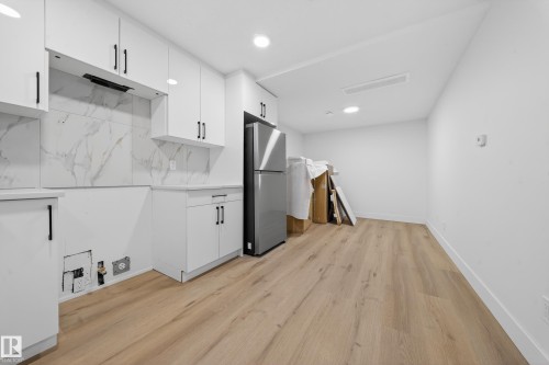 Kitchen with white cabinets, light wood-type flooring, freestanding refrigerator, recessed lighting, and modern cabinets - 132 29 Street, Edmonton, AB - Indoor