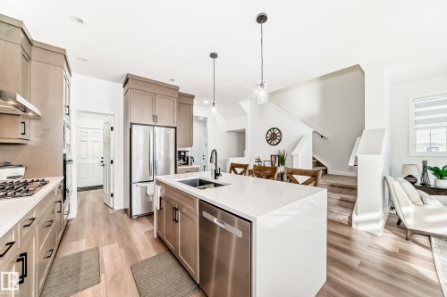 Kitchen featuring stainless steel appliances, light wood-style floors, hanging light fixtures, and a kitchen island with sink - 3569 Erlanger Link, Edmonton, AB - Indoor Photo Showing Kitchen With Double Sink With Upgraded Kitchen