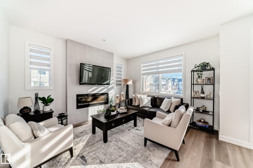 Living area featuring wood finished floors and a large fireplace - 3569 Erlanger Link, Edmonton, AB - Indoor Photo Showing Living Room With Fireplace