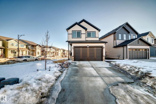 Craftsman house featuring a garage, driveway, a residential view, and stone siding - 3569 Erlanger Link, Edmonton, AB - Outdoor With Facade