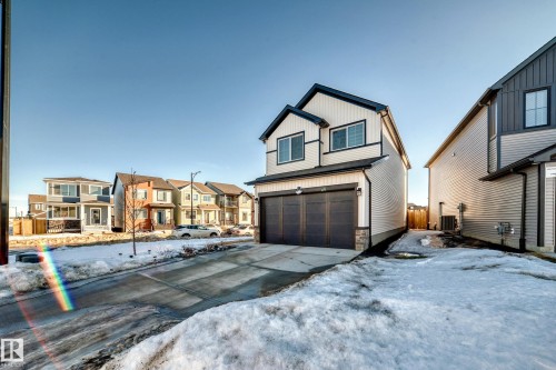 View of front of property featuring driveway, a residential view, an attached garage, and board and batten siding - 3569 Erlanger Link, Edmonton, AB - Outdoor