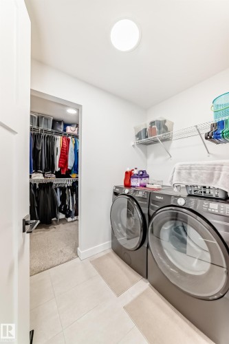 Laundry area featuring separate washer and dryer, light tile patterned flooring, and light colored carpet - 3569 Erlanger Link, Edmonton, AB - Indoor Photo Showing Laundry Room