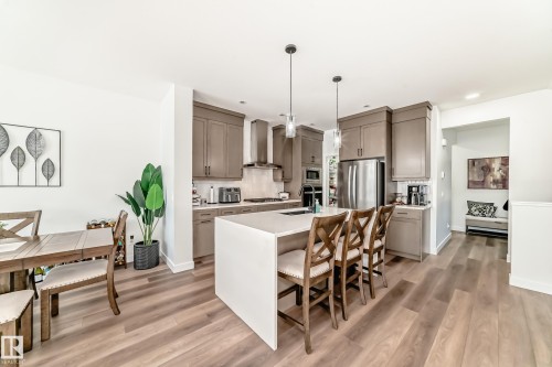Kitchen with a kitchen breakfast bar, pendant lighting, an island with sink, and light wood-style floors - 3569 Erlanger Link, Edmonton, AB - Indoor