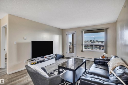 Living room featuring light wood-style floors, a baseboard heating unit, and a textured ceiling - 2405 7343 South Terwillegar Drive, Edmonton, AB - Indoor Photo Showing Living Room