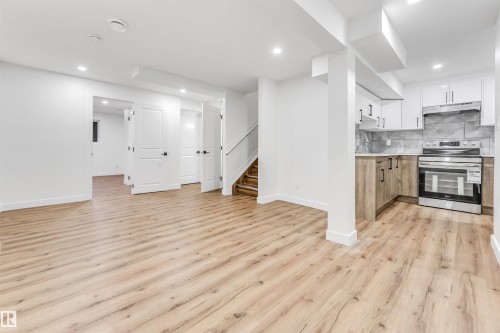 Kitchen with dual tone cabinetry, stainless steel range with electric cooktop, open floor plan, light wood finished floors, and recessed lighting - 4616 32 Avenue, Edmonton, AB - Indoor Photo Showing Kitchen