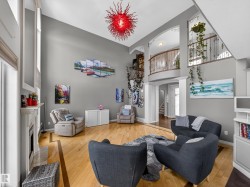 Living area featuring a high ceiling, arched walkways, light wood-style flooring, and a fireplace - 