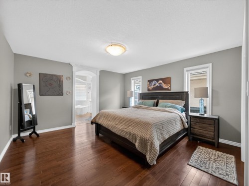 Bedroom with dark wood finished floors, connected bathroom, and a textured ceiling - 1062 Tory Road, Edmonton, AB - Indoor Photo Showing Bedroom