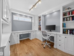 Office space with built in features, built in desk, light wood finished floors, ornamental molding, and rail lighting - 