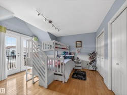 Bedroom with rail lighting, light wood finished floors, french doors, access to outside, and vaulted ceiling - 