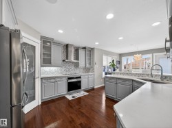 Kitchen featuring gray cabinets, stainless steel appliances, glass fronted cabinets, and dark wood-style flooring - 
