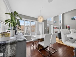 Dining area featuring dark wood-style flooring, a tiled fireplace, and hanging lights - 