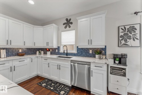 Kitchen with white cabinets, dishwasher, light stone counters, dark wood-style flooring, and recessed lighting - 13 Heron Link, Spruce Grove, AB - Indoor Photo Showing Kitchen With Upgraded Kitchen