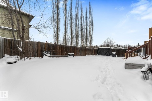 Snowy yard with a fenced backyard and a wooden deck - 13 Heron Link, Spruce Grove, AB - Outdoor