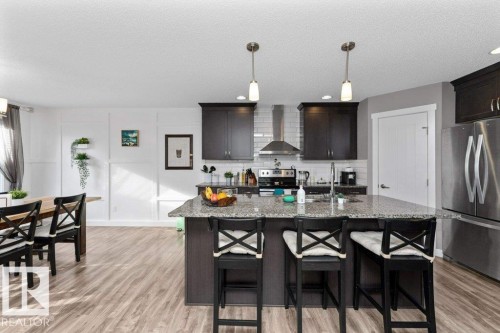 Kitchen with stainless steel appliances, dark stone counters, a breakfast bar, hanging light fixtures, and a center island with sink - 2607 20 Avenue, Edmonton, AB - Indoor Photo Showing Kitchen With Double Sink With Upgraded Kitchen