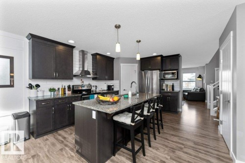 Kitchen featuring a breakfast bar, an island with sink, stainless steel appliances, light wood-type flooring, and pendant lighting - 2607 20 Avenue, Edmonton, AB - Indoor Photo Showing Kitchen With Upgraded Kitchen