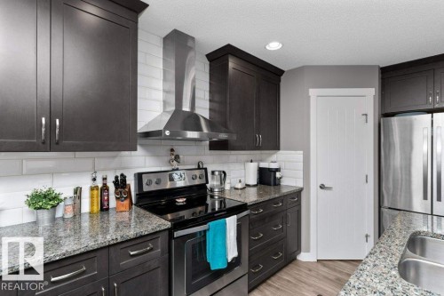 Kitchen with stainless steel appliances, light stone countertops, backsplash, light wood-style floors, and recessed lighting - 2607 20 Avenue, Edmonton, AB - Indoor Photo Showing Kitchen With Double Sink With Upgraded Kitchen