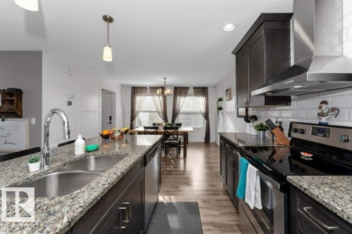 Kitchen with stainless steel appliances, light stone countertops, light wood-type flooring, a textured ceiling, and a chandelier - 2607 20 Avenue, Edmonton, AB - Indoor Photo Showing Kitchen With Double Sink With Upgraded Kitchen
