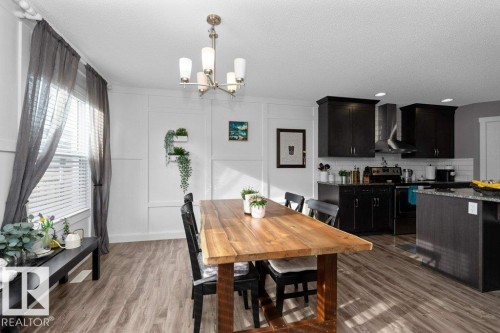 Dining area featuring a decorative wall, hanging lights, dark wood-type flooring, and a textured ceiling - 2607 20 Avenue, Edmonton, AB - Indoor Photo Showing Dining Room