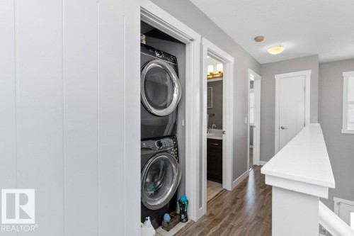 Laundry area featuring dark wood-style flooring and stacked washing machine and dryer - 2607 20 Avenue, Edmonton, AB - Indoor Photo Showing Laundry Room