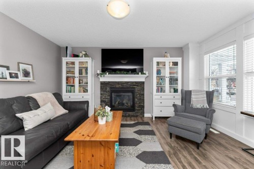 Living room featuring a fireplace, dark wood-type flooring, and a textured ceiling - 2607 20 Avenue, Edmonton, AB - Indoor Photo Showing Living Room With Fireplace