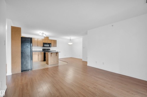 Unfurnished living room featuring light wood finished floors and rail lighting - 422 7909 71 Street, Edmonton, AB - Indoor Photo Showing Kitchen