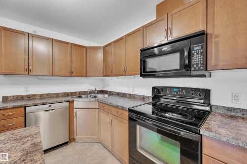 Kitchen with black appliances, wood finish cabinetry, and dark countertops - 422 7909 71 Street, Edmonton, AB - Indoor Photo Showing Kitchen
