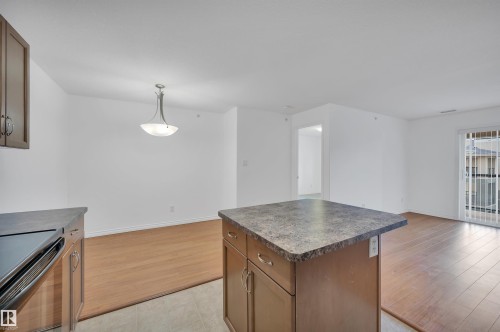 Kitchen with dark countertops, wood finish cabinetry, a kitchen island, and hanging light fixtures - 422 7909 71 Street, Edmonton, AB - Indoor Photo Showing Kitchen
