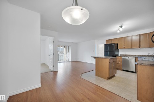 Kitchen with stainless steel dishwasher, open floor plan, freestanding refrigerator, a center island, and hanging light fixtures - 422 7909 71 Street, Edmonton, AB - Indoor Photo Showing Kitchen