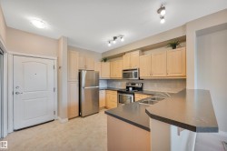 Kitchen featuring stainless steel appliances, light wood finish cabinetry, backsplash, a peninsula, and a kitchen bar - 