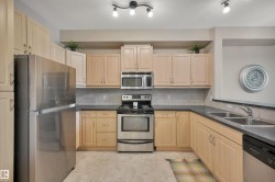 Kitchen featuring stainless steel appliances, light wood finish cabinets, and decorative backsplash - 