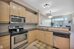 Kitchen with stainless steel appliances, dark countertops, hanging light fixtures, tasteful backsplash, and a peninsula - 