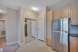 Kitchen featuring freestanding refrigerator, light wood finish cabinets, and a textured ceiling - 