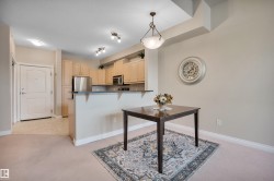 Kitchen featuring dark countertops, hanging light fixtures, a kitchen breakfast bar, light wood finish cabinets, and a peninsula - 