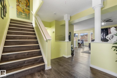 Stairs featuring decorative columns, a textured ceiling, wood finished floors, and a ceiling fan - 13148 151 Avenue, Edmonton, AB - Indoor Photo Showing Other Room