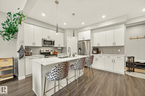 Kitchen featuring a kitchen bar, a kitchen island with sink, stainless steel appliances, and dark wood finished floors - 74 Royal Street, St. Albert, AB - Indoor Photo Showing Kitchen With Double Sink With Upgraded Kitchen