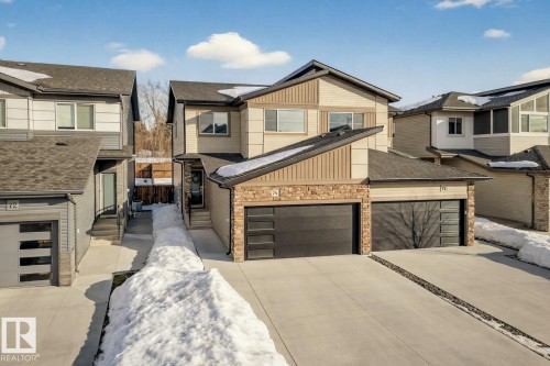 View of front facade featuring concrete driveway, stone siding, a residential view, and board and batten siding - 74 Royal Street, St. Albert, AB - Outdoor