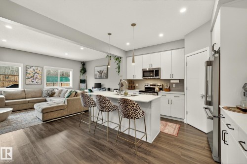 Kitchen with an island with sink, white cabinetry, stainless steel appliances, a breakfast bar area, and hanging light fixtures - 74 Royal Street, St. Albert, AB - Indoor
