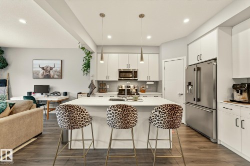 Kitchen featuring open floor plan, stainless steel appliances, a breakfast bar area, white cabinets, and an island with sink - 74 Royal Street, St. Albert, AB - Indoor Photo Showing Kitchen With Stainless Steel Kitchen With Upgraded Kitchen