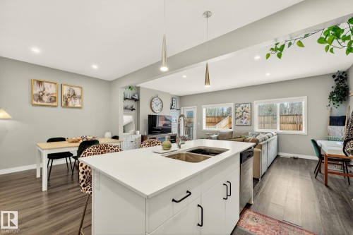 Kitchen featuring white cabinetry, dark wood-style floors, open floor plan, and hanging light fixtures - 74 Royal Street, St. Albert, AB - Indoor Photo Showing Kitchen With Double Sink