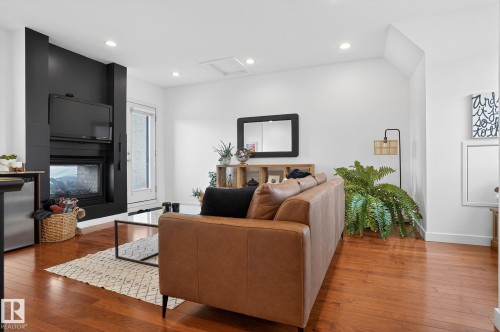 Living area featuring a large fireplace, hardwood / wood-style floors, and recessed lighting - 1 9561 143 Street Nw, Edmonton, AB - Indoor Photo Showing Living Room